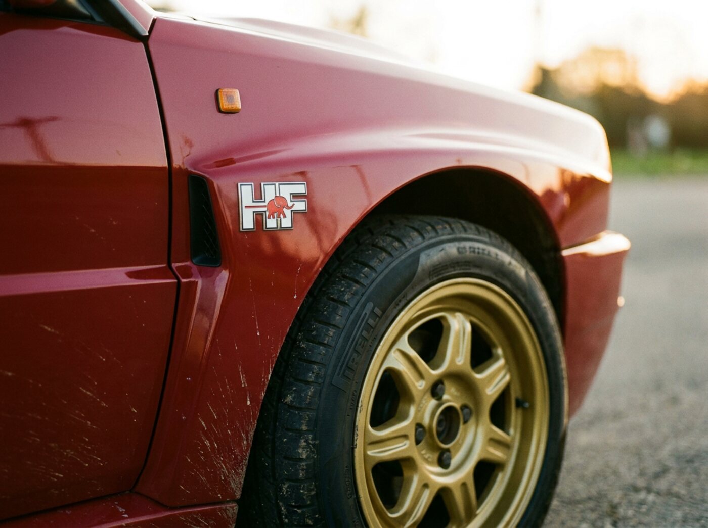 Détail Delta Integrale : aile élargie sur jante dorée avec badge HF