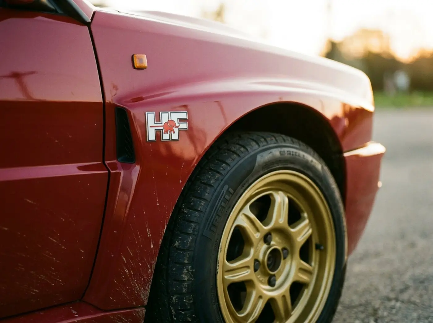 Détail Delta Integrale : aile élargie sur jante dorée avec badge HF