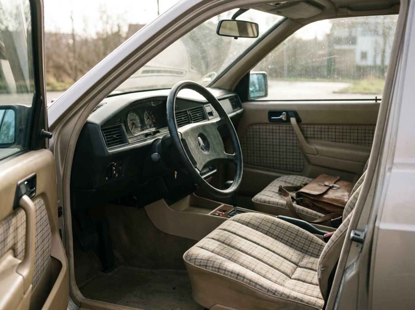 Intérieur Mercedes 190E : sièges en tissu à carreaux, grand volant fin et planche de bord sobre